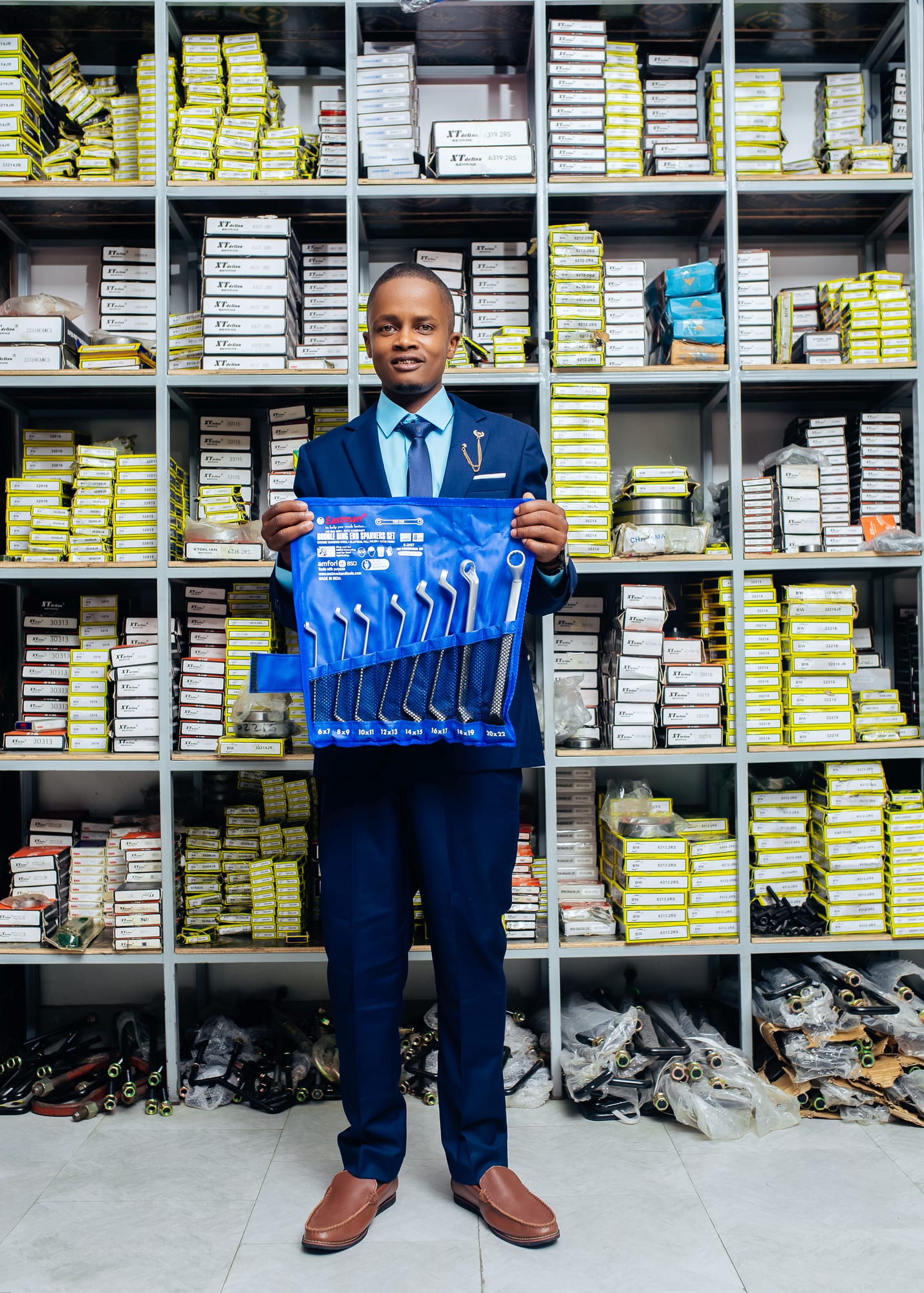 Showroom shelving stocked with boxed bearings, with a Chasama staff member holding a spanner set